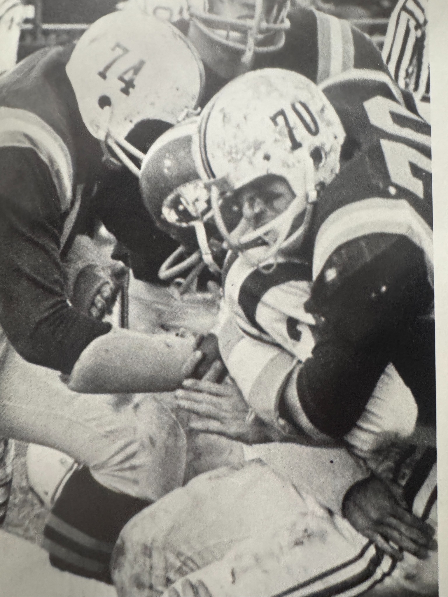 Helmeted football players seated on the sideline.